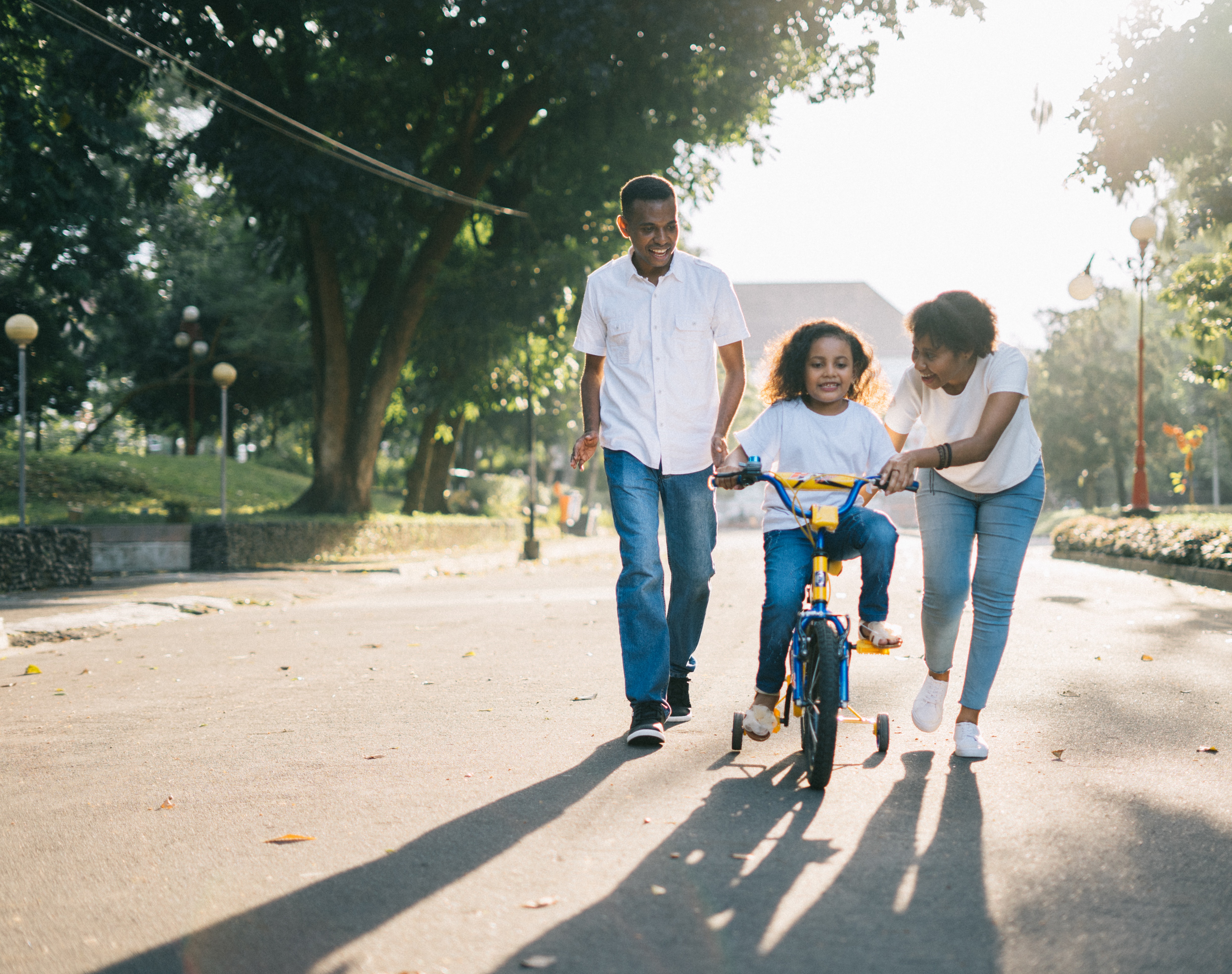 Criança aprendendo a andar de bicicleta com os pais